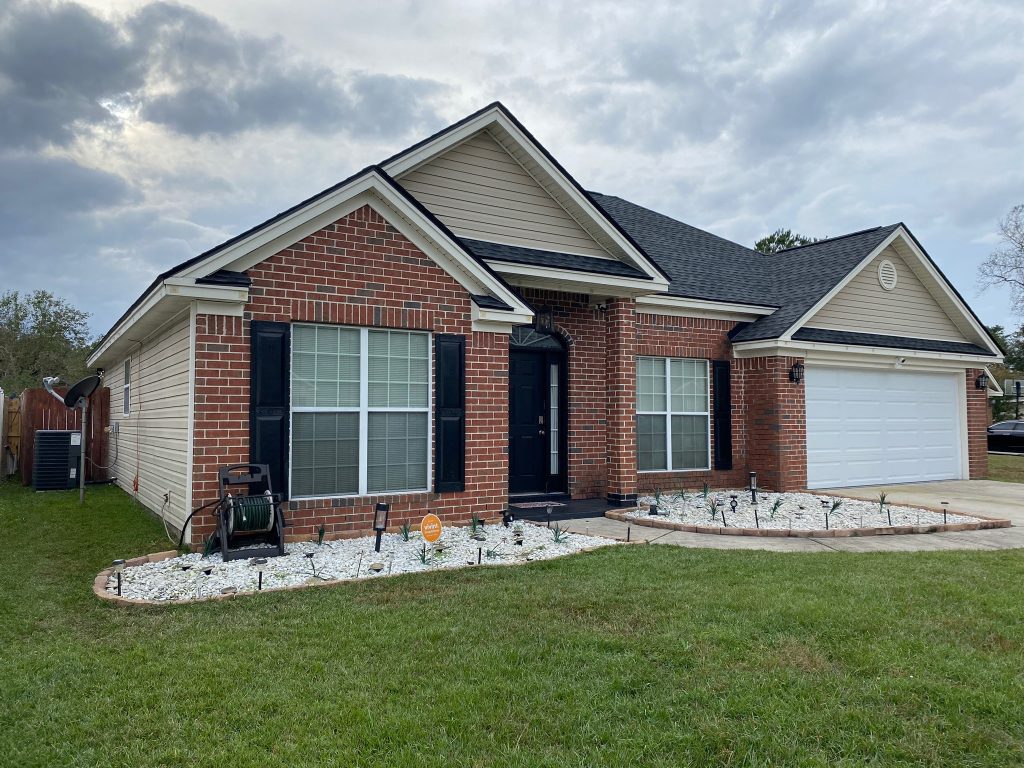 Single-story tan home with a two-car garage and freshly installed shingle roof in Savannah, GA