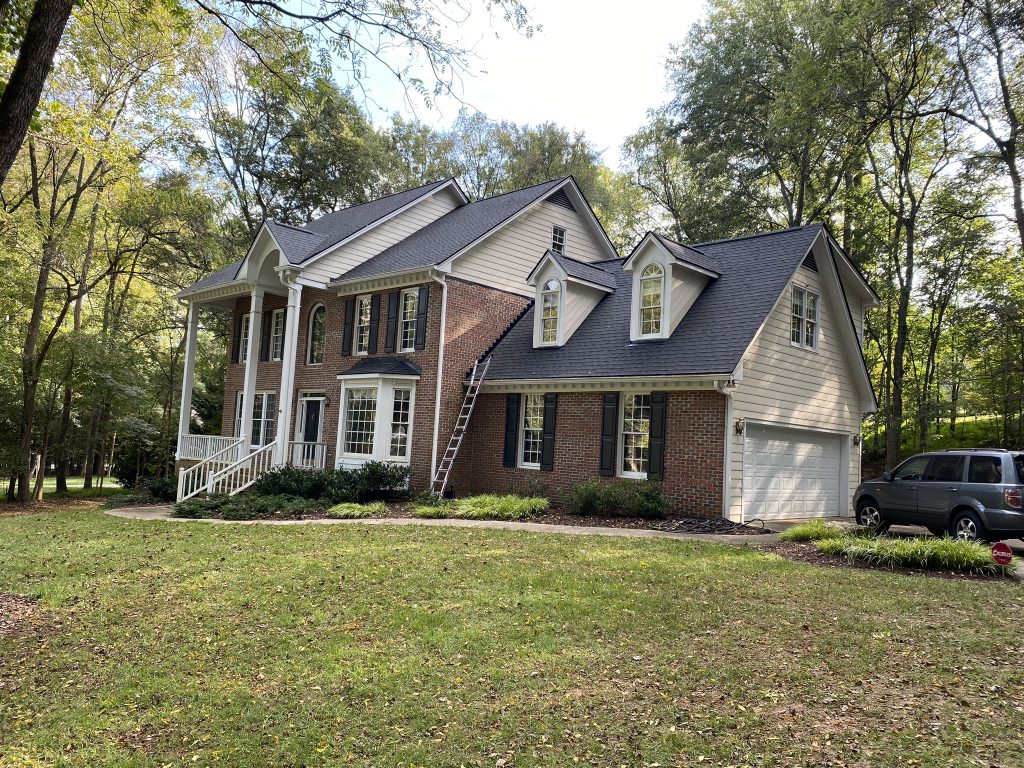 Two-story home with white trim and a freshly installed dark shingle roof in Raleigh, NC