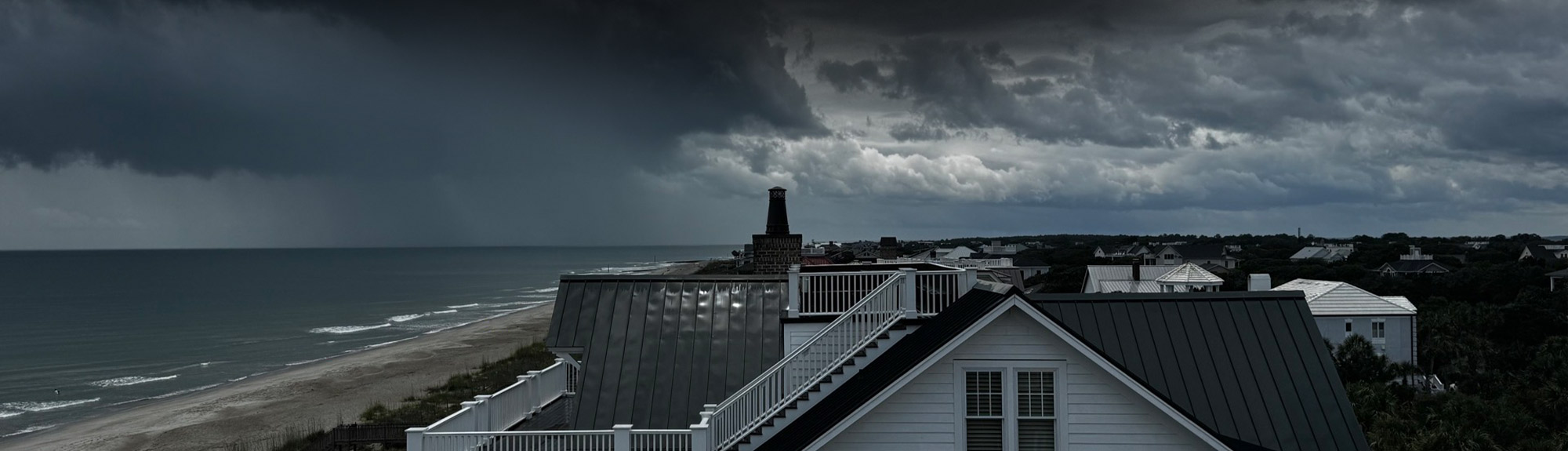 Storm clouds rolling in over a coastal home with a standing seam metal roof