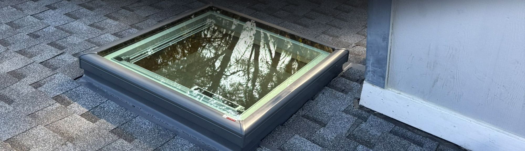 New skylight installed with metal flashing in an asphalt shingle roof
